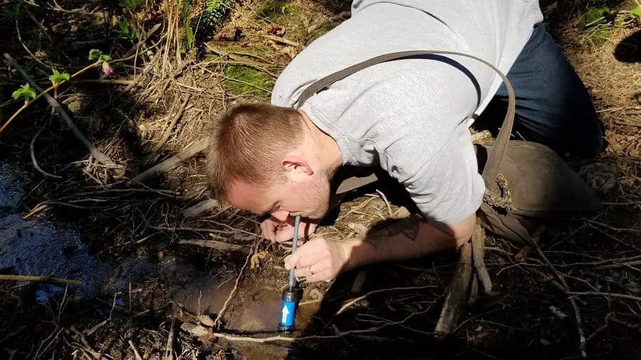 Sawyer Mini Water Filter drinking from a river