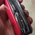 compact edc knife with multiple blades and red grip