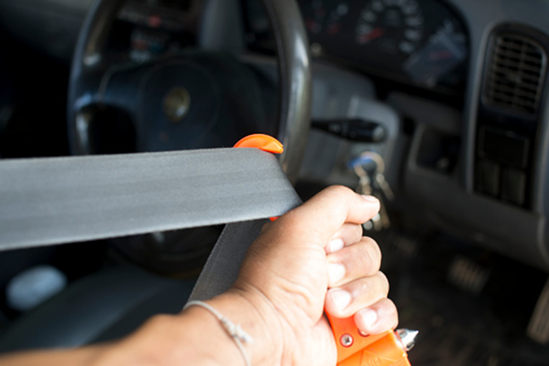 cutting through a jammed seatbelt with a seatbelt cutter